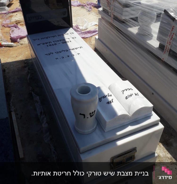 מצבה עם כיתוב בעברית, אגרטל וספרים מעוצבים